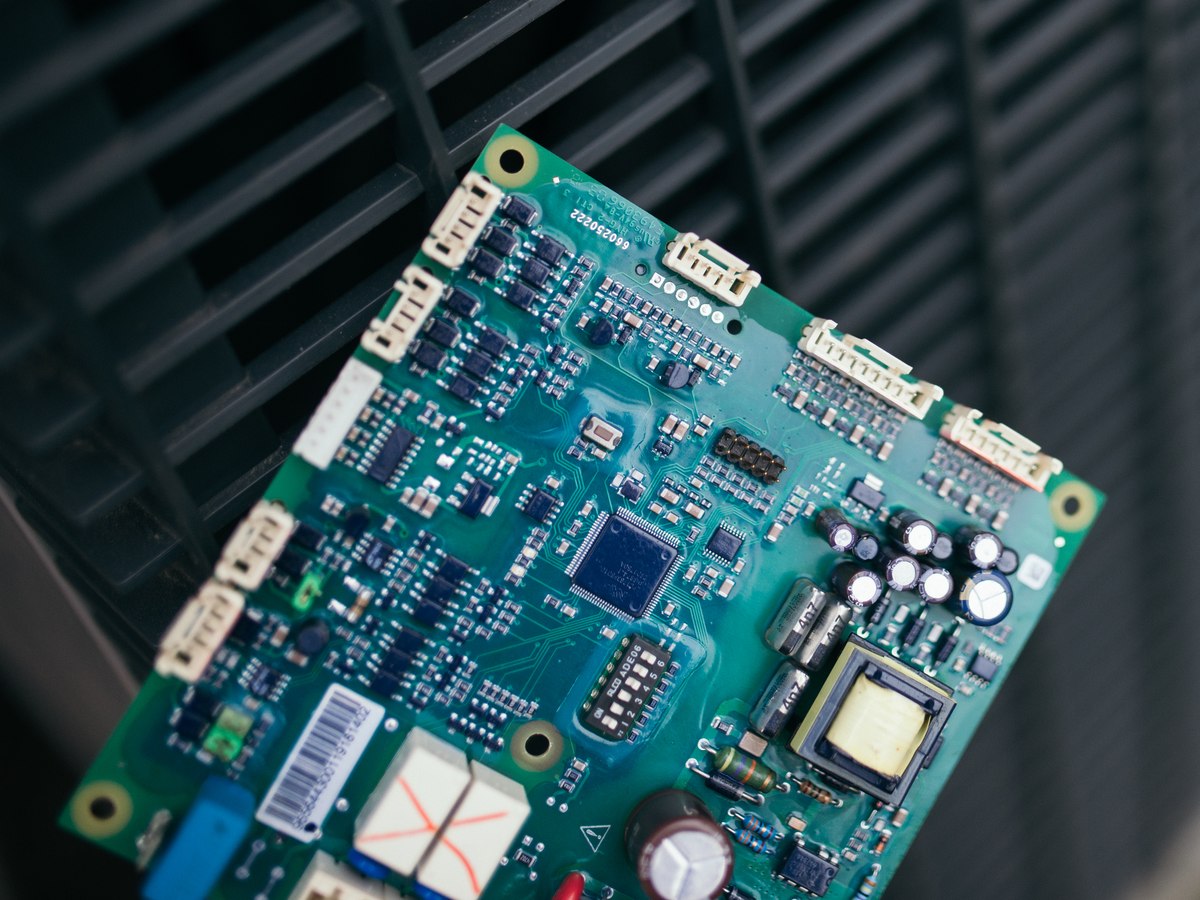 Placa eletrônica de ar-condicionado fotografada de perto durante diagnóstico técnico